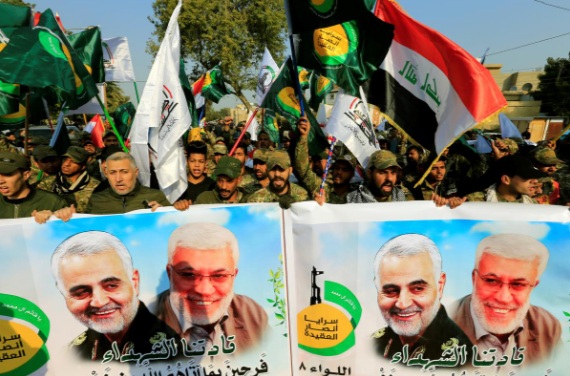Các binh sĩ đem theo ảnh của chỉ huy lực lượng quân sự Iraq Abu Mahdi al-Muhandis (phải) và tướng Qassem Soleimani, chỉ huy lực lượng Quds của Iran (trái) - Ảnh: Reuters.