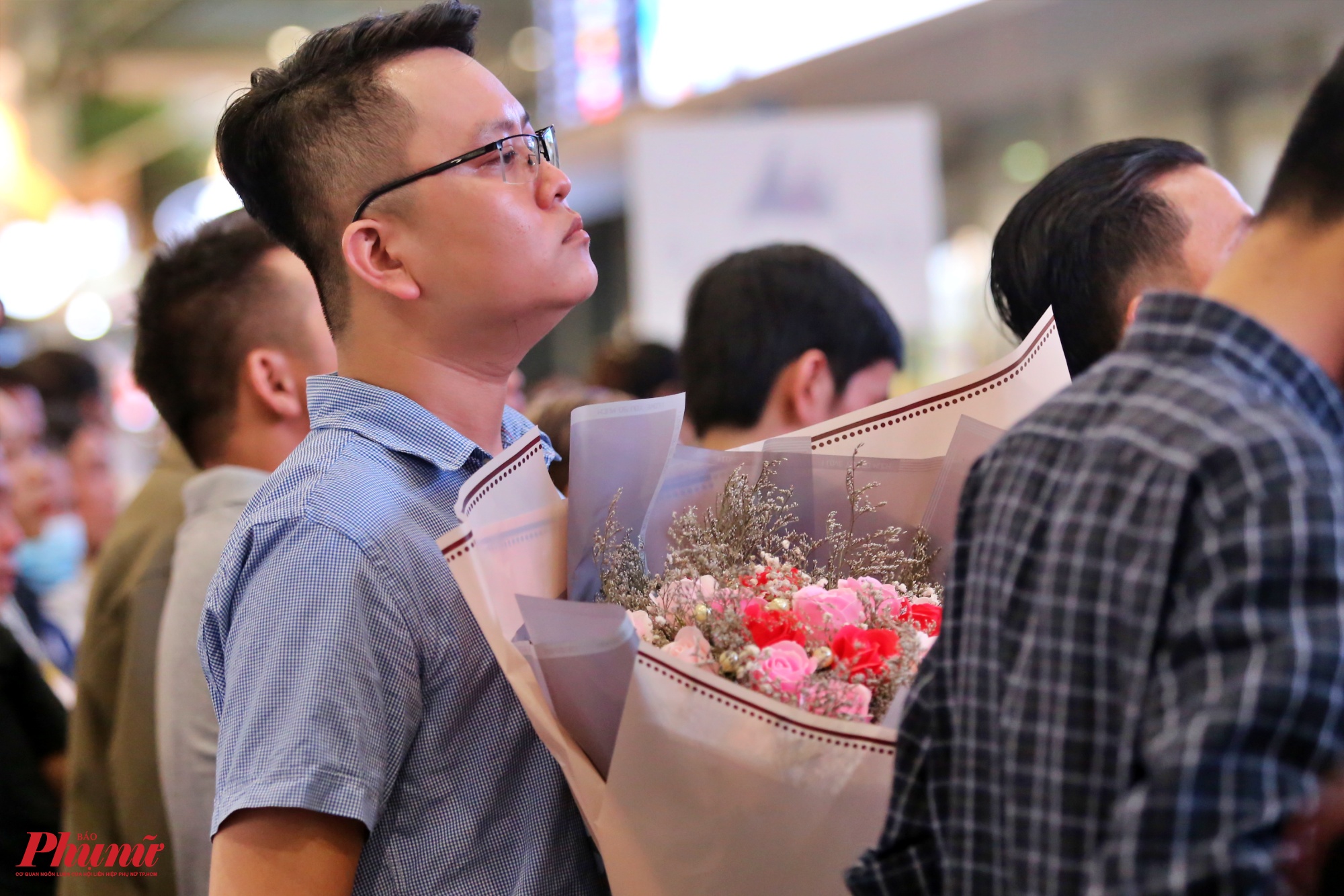 Nhiều người mang theo hoa và quà đứng ngồi nhấp nhổm để tìm ra bóng dáng người thân quen đang lẫn trong các hành khách khác.