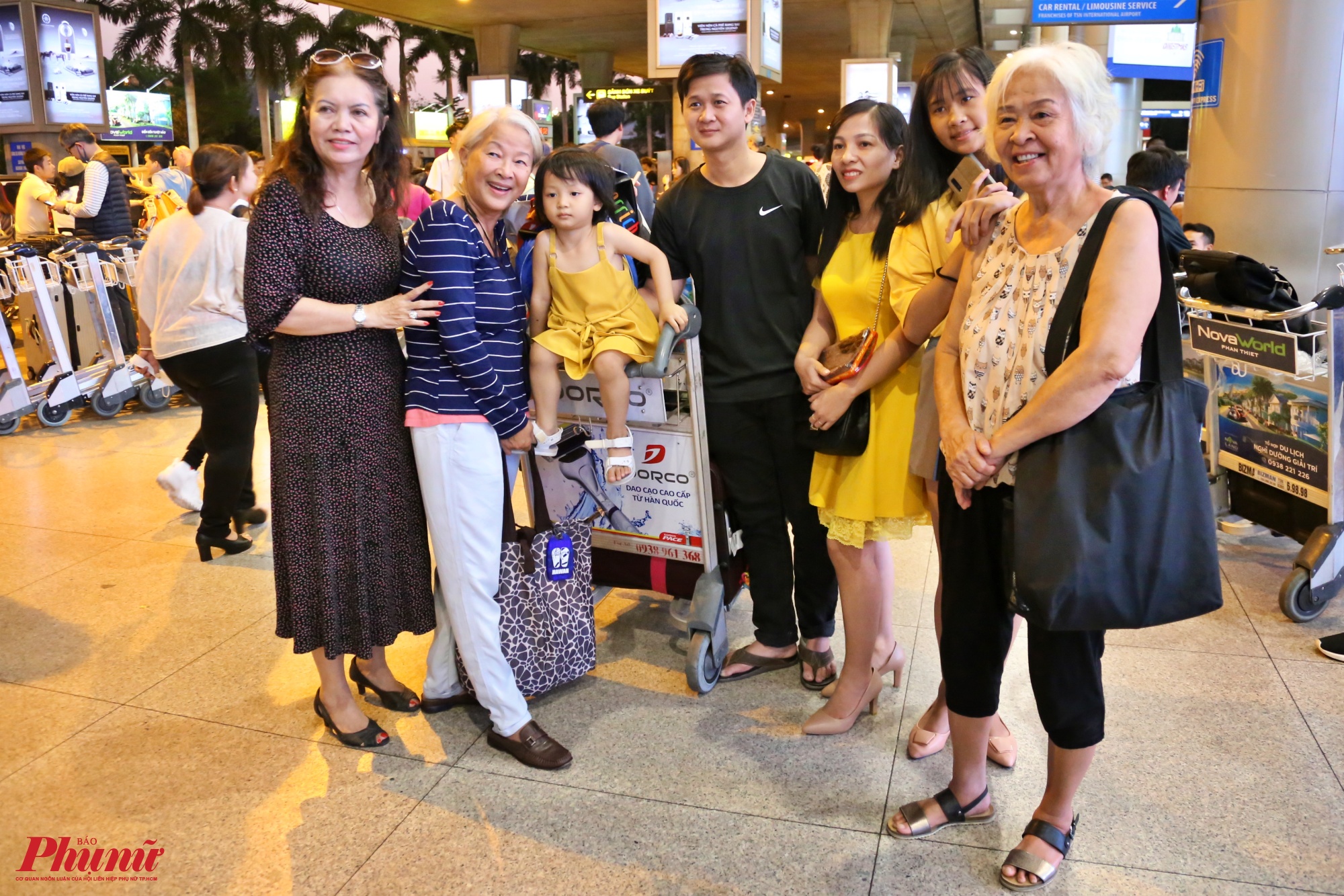 Một gia đình tươi cười chụp ảnh lưu niệm đoàn tụ ở sân bay