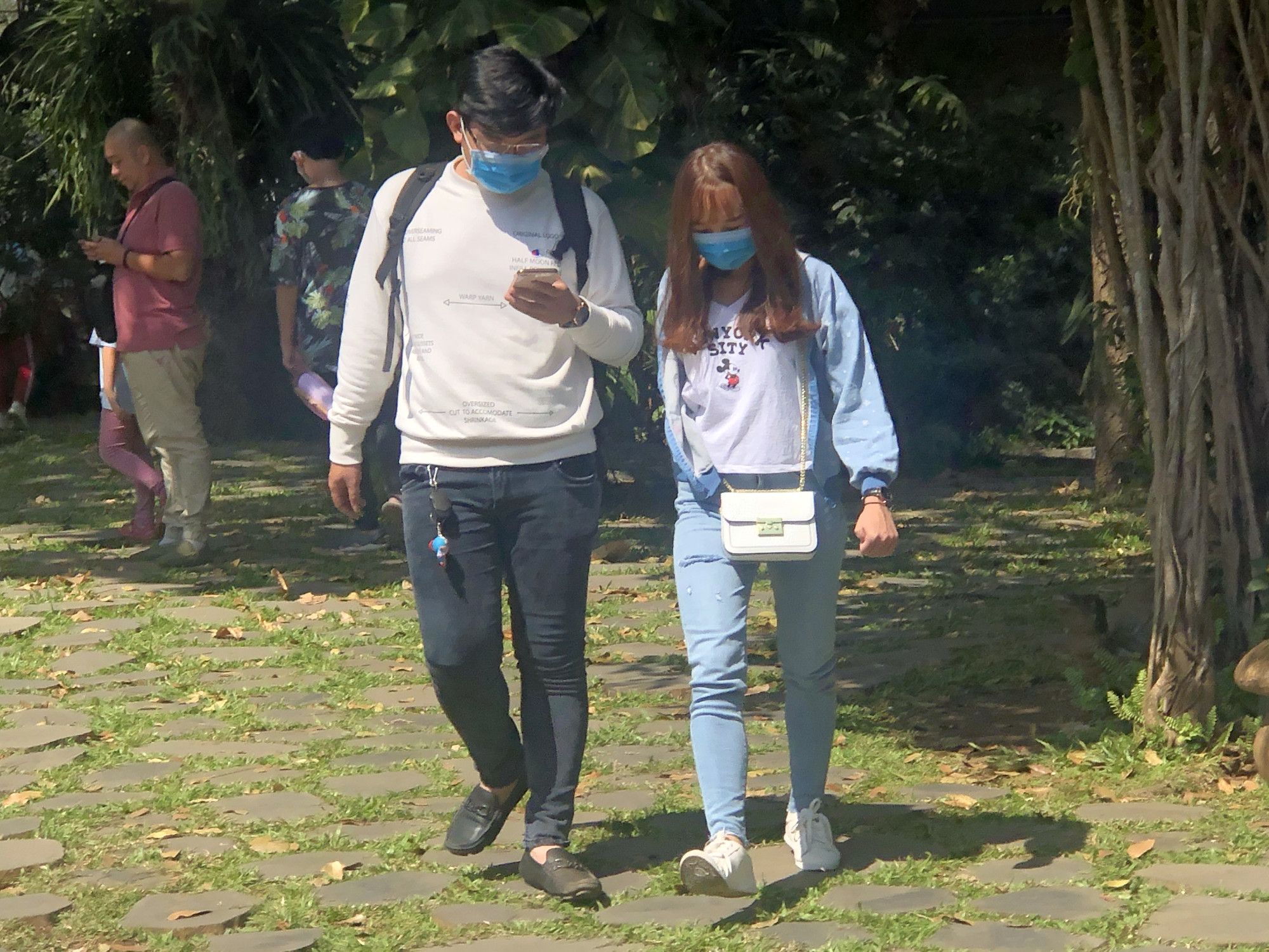 Hai bạn trẻ đang đi dạo trong sân chùa Bửu Long nhưng vẫn không quên đeo khẩu trang