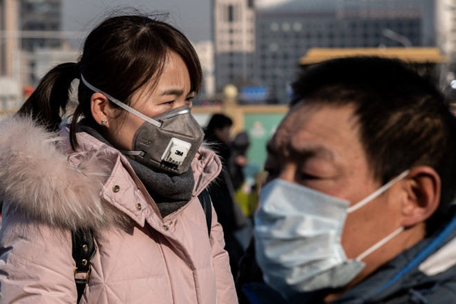 Người dân đeo khẩu trang gần một trạm xe điện tại Bắc Kinh AFP