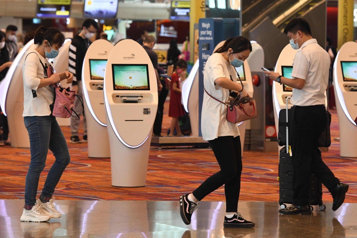 Du khách đeo khẩu trang tại sân bay quốc tế Changi ở Singapore - Ảnh: AFP