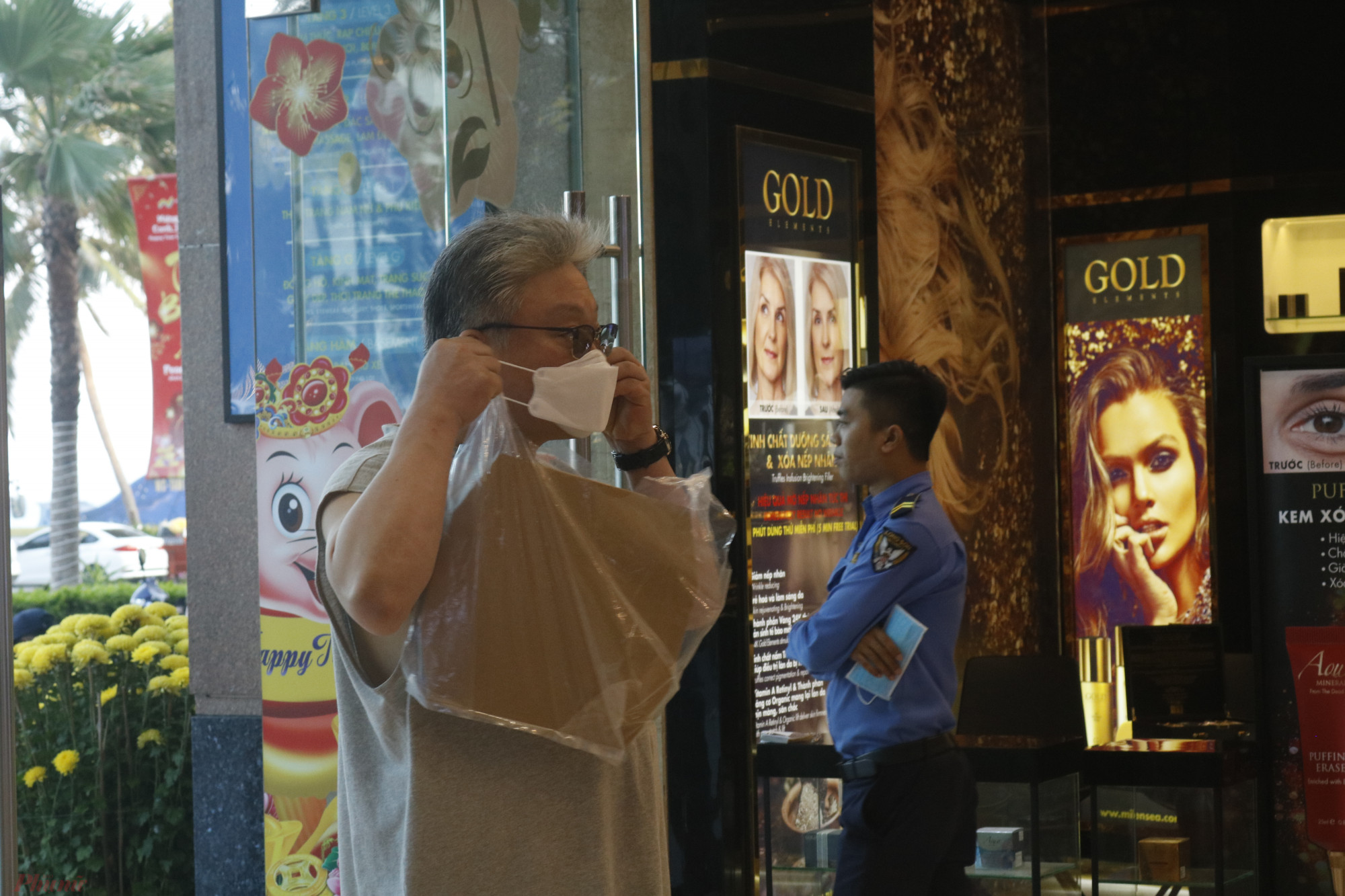 Một người khách ngoại quốc đeo khẩu trang bước vào trung tâm thương mại.