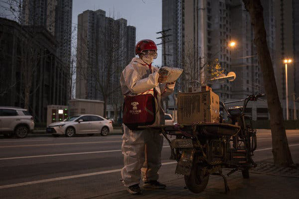Người giao hàng làm việc giữa thành phố Vũ Hán trong trang phục bảo hộ 
