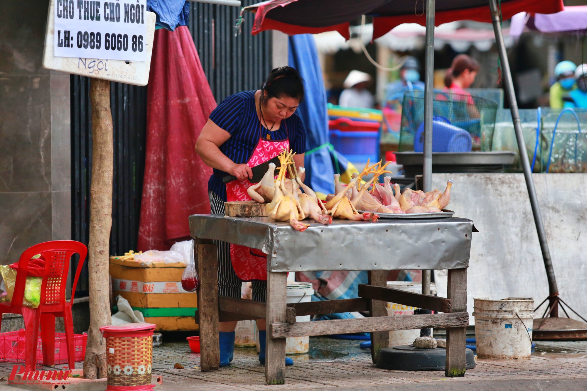 Một người phụ nữ bày bán thịt gà sống làm sẵn ngay dưới chân chợ Cầu, quận 12 