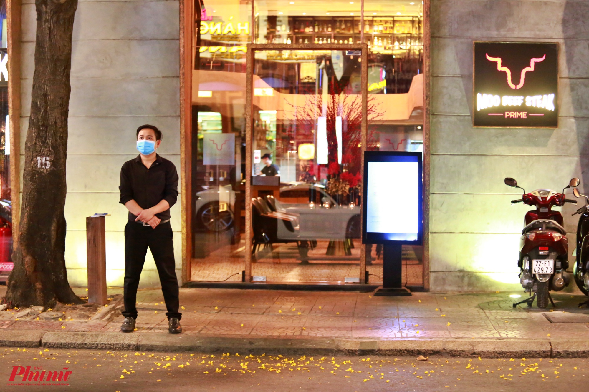 Một nhân viên nhà hàng bịt khẩu trang đợi khách ở đường Ngô Đức Kế
