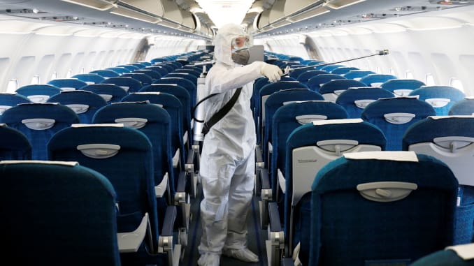 Nhân viên y tế phun thuốc khử trùng bên trong một chiếc máy bay của Vietnam Airlines tại sân bay Nội Bài ở Hà Nội, Việt Nam, để ngăn chặn sự lây lan của virus - Ảnh: Reuters