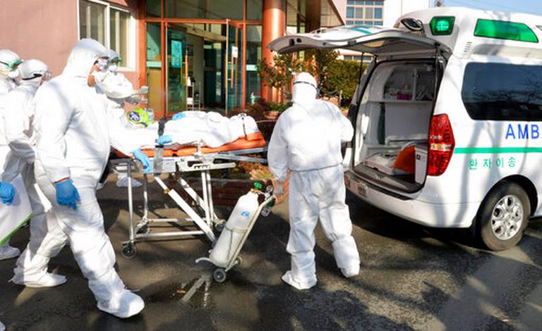 Nhân viên y tế đưa một người bị nghi nhiễm COVID-19 tại bệnh viện Daenam, quận Cheongdo lên xe cứu thương hôm 21/2.