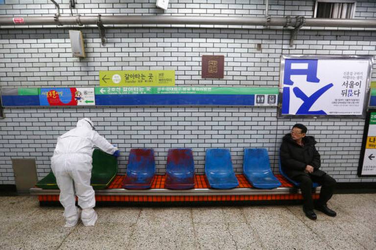Nhân viên y tế khử trùng băng ghế tại một ga tàu điện ở Seoul.