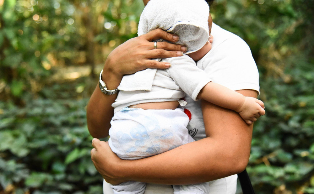 Christine ẵm con trai trên tay, chờ đợi một người sẵn sàng trả 200 USD để nhận nuôi đứa bé - Ảnh: Media Corp