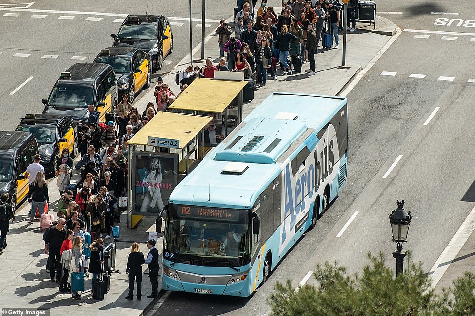 Các du khách xếp hàng chờ lên xe buýt ra sân bay tại Barcelona, hôm 15/3.