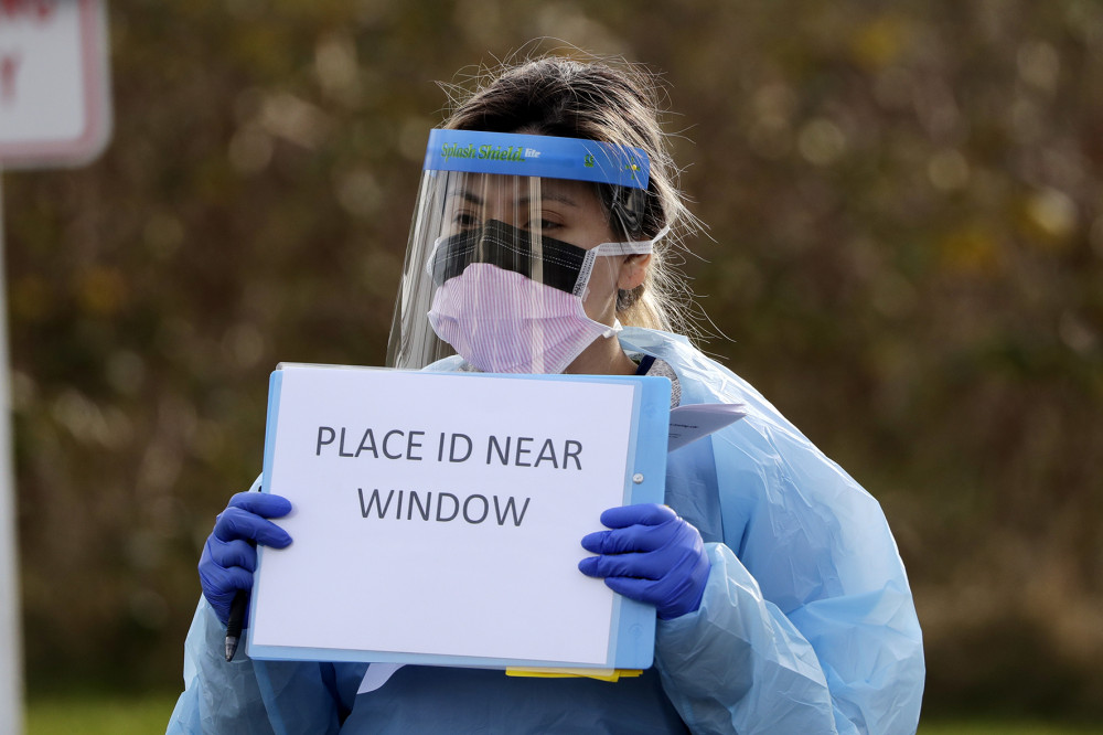 Trợ lý y tế Miriam Fuentes dùng bảng hướng dẫn mọi người tới xét nghiệm virus ở Đại học Y khoa Washington. Washington là bang bị ảnh hưởng nặng nề, có nhiều ca tử vong vì COVID-19 nhất ở Hoa Kỳ. Ảnh: Elaine Thompson (AP Photo).