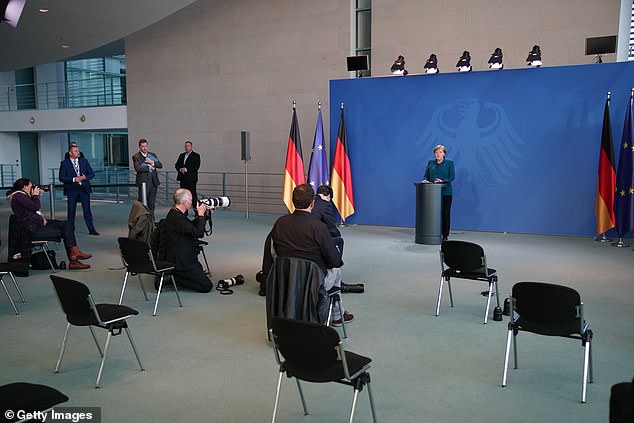 CÁc phóng viên và nhân viên giữ tuân thủ khoảng cách quy định trong một buổi họp báo của bà Merkel.