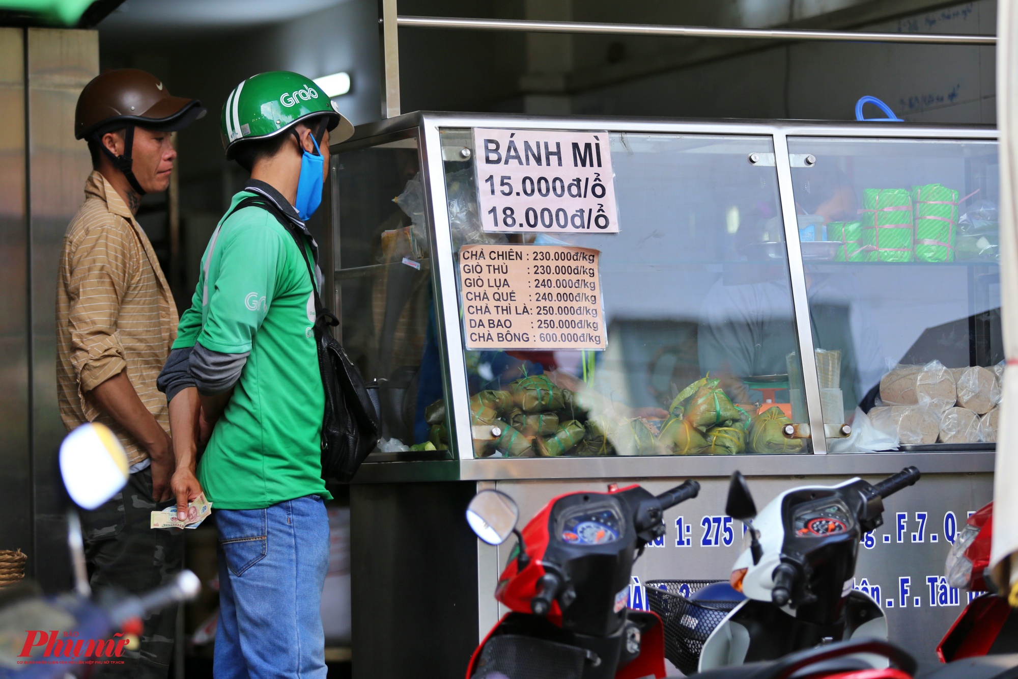 Một nhân viên đứng đợi mua bánh mỳ để giao cho khách trên đường Hoàng Hoa Thám, quận Tân Bình.