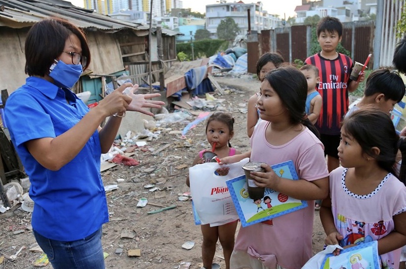 Đoàn viên Chi đoàn Báo Phụ Nữ TPHCM hướng dẫn các em nhỏ tại xóm Chùa cách đeo khẩu trang, rửa tay và tuyên truyền về các biện pháp phòng tránh dịch COVID-19.