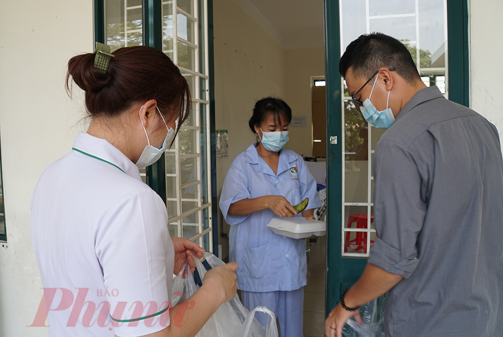 Nhân viên y tế nhận cơm, mang lên các tầng lầu cho những người đang cách ly