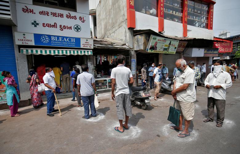 Người dân xếp hàng mua thuốc phải đứng trong những ô tròn được kẻ bằng phấn để giữ khoảng cách an toàn vào ngày 26/3 tại Ahmedabad.