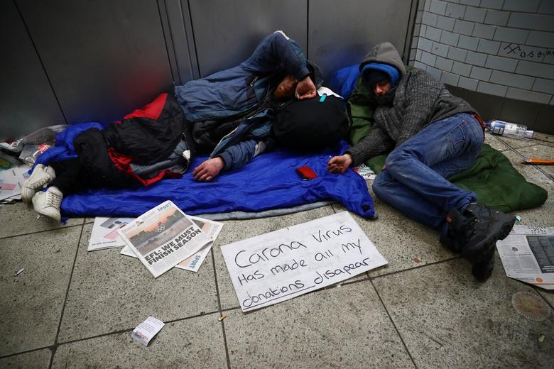 Người vô gia cư nằm vật vạ ở nhà ga tại Westminster vào ngày 19/3. Ho ghi tấm bảng với nội dung virus corona đã làm cho mọi nguồn tiếp tế biến mất.