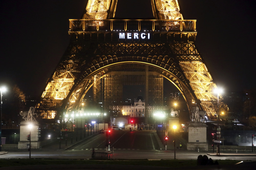 Băng-rôn mang từ MERCI (Cám ơn, trong tiếng Pháp) được treo trên tháp Eiffel tại thủ đô Paris, trong một chương trình tri ân lớn nhằm cám ơn và cổ vũ đội ngũ y tế đang vất vả chiến đấu để cứu người và ngăn đại dịch Covid-19 hoành hành ở Pháp. Hình của Thibault Camus, chụp ngày 27 tháng 3 năm 2020 (AP Photo).
