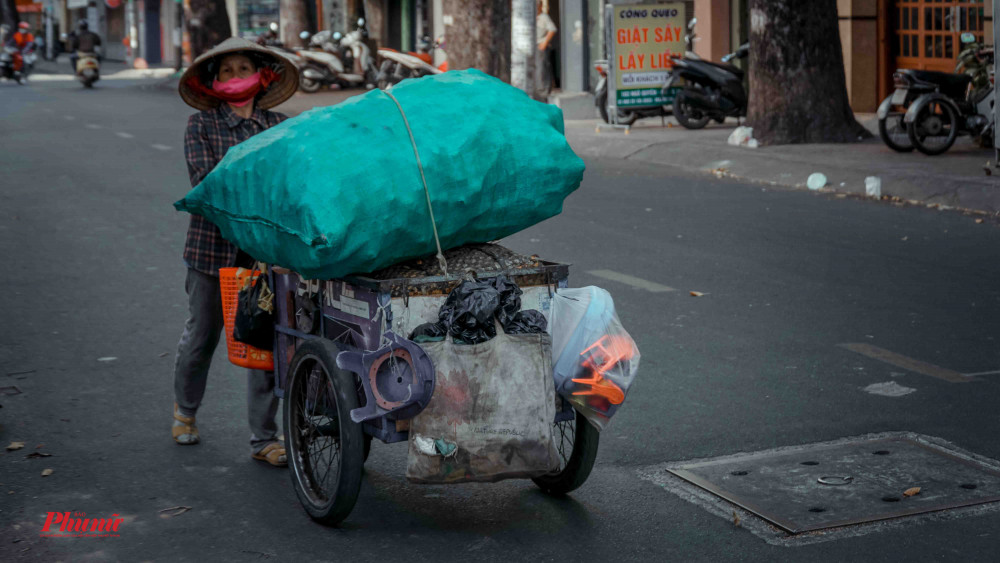 Chị Năm bên cạnh chiếc xe đẩy đi khắp Sài Gòn nhặt ve chai nuôi các con ăn học suốt 7 năm trời