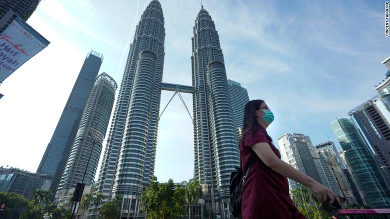 Một phụ nữ Malaysia đeo khẩu trang đi ngang tòa tháp Twin Towers ở Kuala Lumpur. Ảnh: CNN