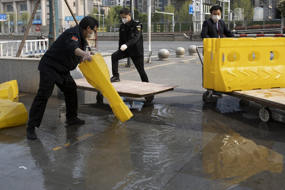 Nhân viên thành phố Vũ Hán dọn dẹp các rào cản trên đường phố sau 76 ngày phong tỏa - Ảnh: AP