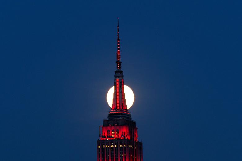 Mặt trăng như bị cắt làm đôi bởi đỉnh chóp nhọn của toà nhà cao 102 tầng Empire State Building ở New York.