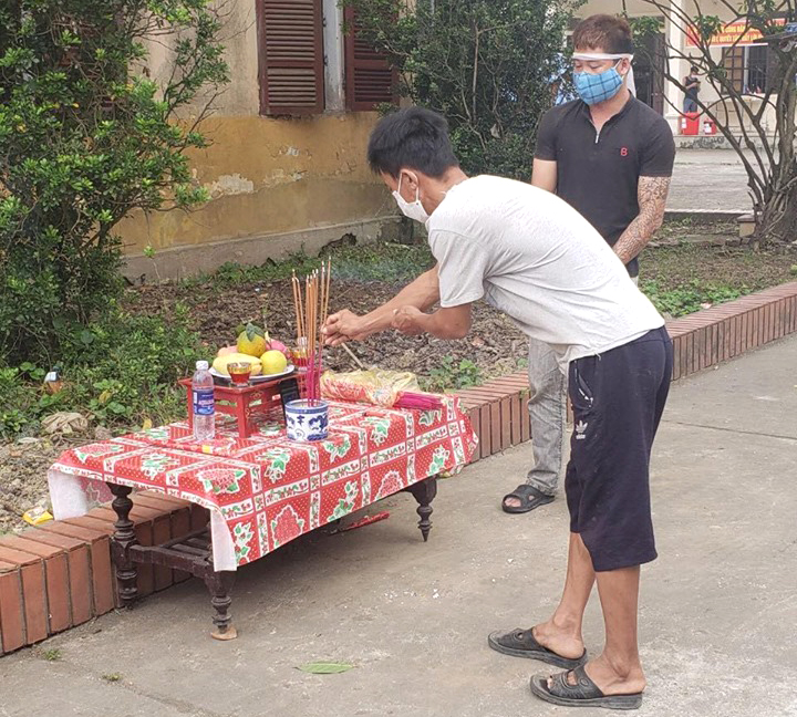 Anh Dũng chít khăn tang, đứng cạnh bàn thờ vái tạ những người đến viếng cha mình