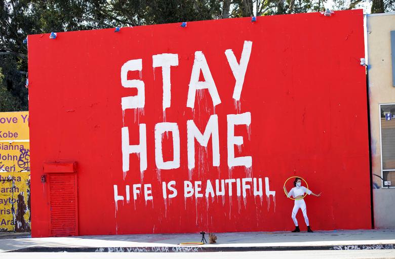 Một vũ công đang thực hiện một đoạn video bên cạnh bức tường đỏ, nổi bật lên dòng chữ trắng với thông điệp: 