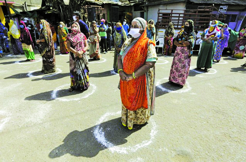 Những phụ nữ tại Ahmedabad, Ấn Độ giữ đúng khoảng cách được khuyến nghị khi đợi tổ chức từ thiện đến phát khẩu trang, nước rửa tay