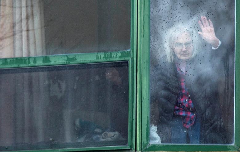 Một bà cụ vẫy tay từ cửa sổ phòng để chào người quá cố sau khi nơi đây có 31 trường hợp