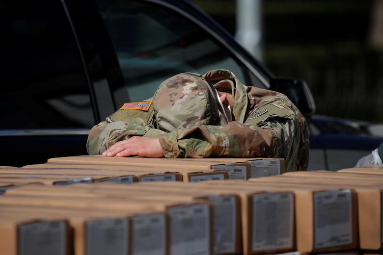 Lực lượng quân đội Mỹ được huy động để hỗ trợ công tác phòng, chống dịch. Một thành viên của lực lượng này tranh thủ chợp mắt nghỉ ngơi trên những hộp thức ăn cứu trợ được chuẩn bị phân phát cho người dân ở New York.
