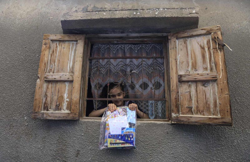Ở Palestine, một cô gái khoe gói đọc tài liệu và đồ dùng nghệ thuật mà các tình nguyện viên phân phát cho trẻ em bị cô lập.