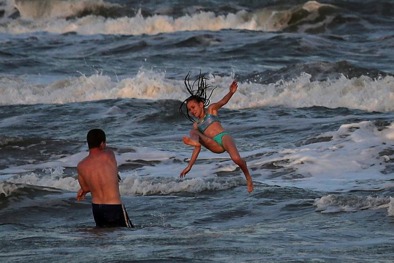 Troy Aller ném em họ Taliyah, 10 tuổi, lên sóng tại một bãi biển kín ở Surfside Beach, Texas