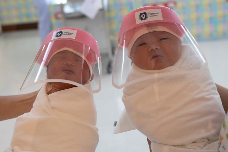 Hai em bé chào đời hôm 9/4 tại bệnh viện ở Băng Cốc, Thái Lan được đeo mũ bảo hộ để tránh lây nhiễm dịch bệnh.