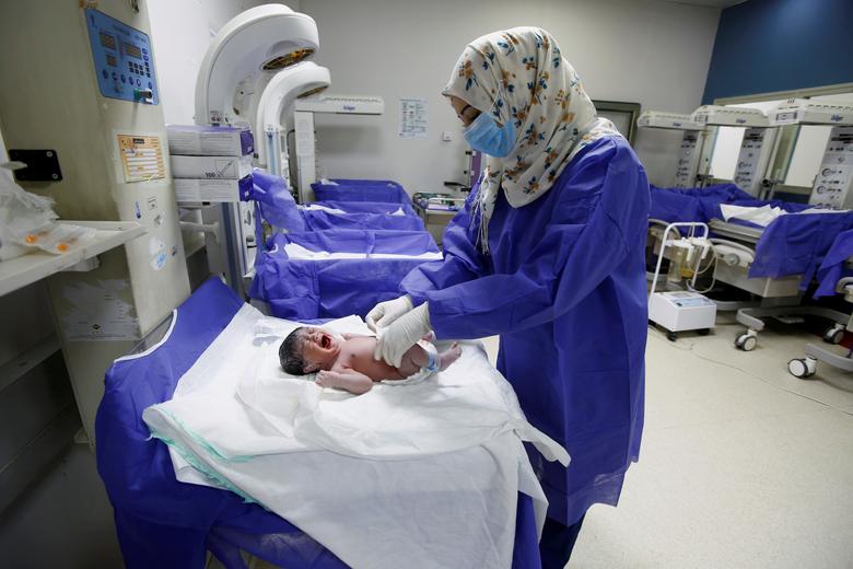Nữ y tá trong một bệnh viện ở Najab, Iraq đeo khẩu trang, mang găng tay cẩn thận khi chăm sóc cho một em bé vừa chào đời.
