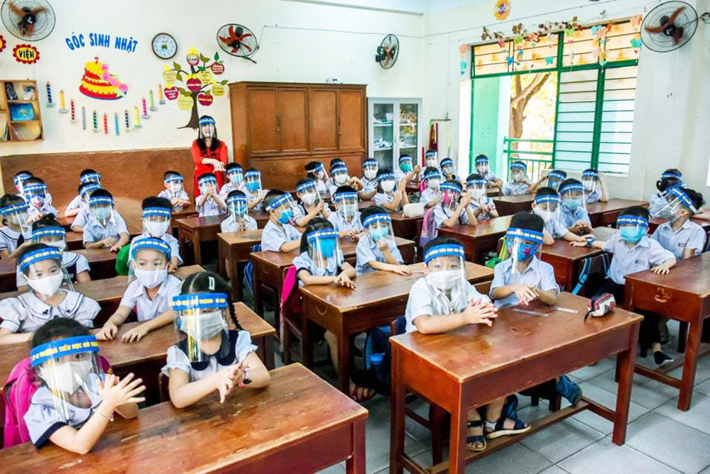 Học sinh Trường tiểu học Núi Thành (TP.Đà Nẵng) đeo nón chắn giọt bắn khi tới trường