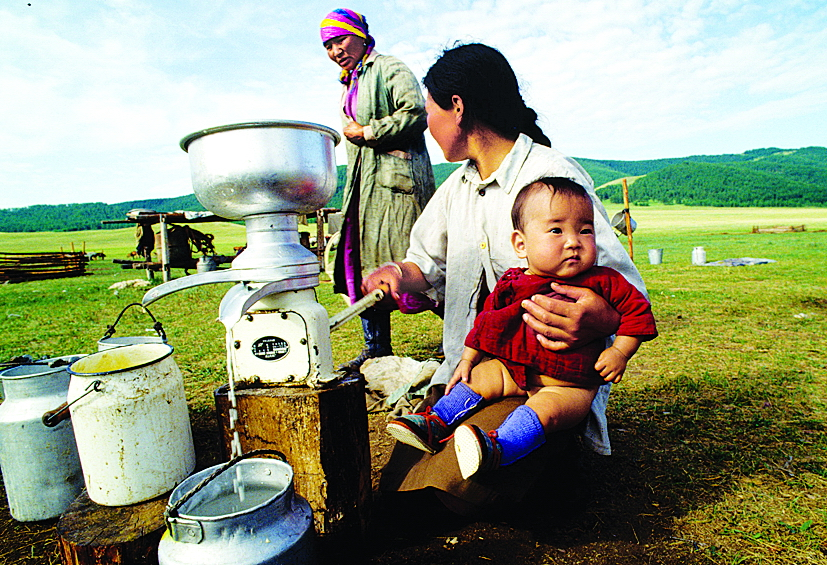 Giữa thảo nguyên Mông Cổ bao la, người mẹ này một tay đánh kem, một tay ôm con trai. Người mẹ tất bật trọn một ngày đến mức chị chẳng thể phân biệt đâu là thời gian dành cho công việc, đâu là thời gian dành riêng cho con. Với chị, đó chính là guồng quay của cuộc sống - Ảnh: Getty Images