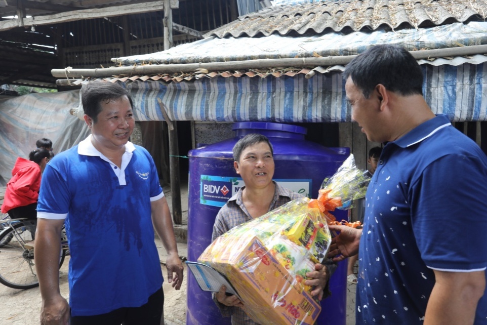 Anh Lê Huỳnh – Phó giám đốc BIDV Cà Mau cùng nghệ sĩ Quyền Linh trao tặng quà và bồn chứa nước cho người dân. Ảnh: BIDV cung cấp