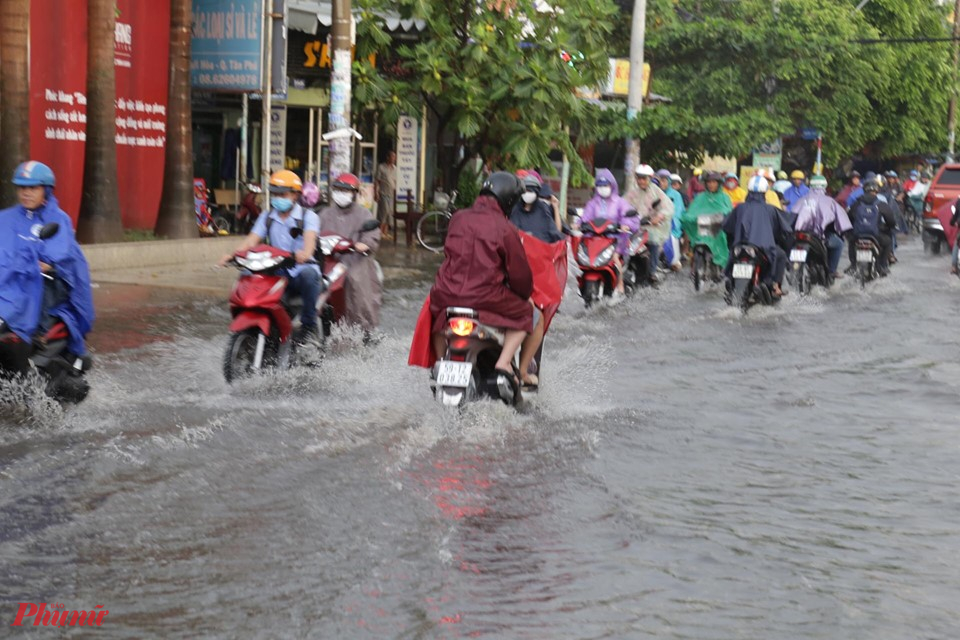 Người dân bì bõm lội nước ngập về nhà sau mưa dông mạnh