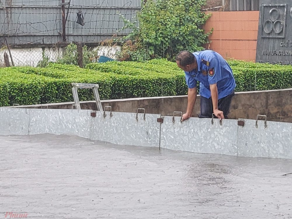 Nước ngập ngày càng cao, nhân viên bảo vệ phải đội mữa giữ tấm chắn không cho nước ngập xô ngã.