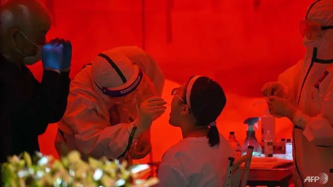 Một nhân viên y tế lấy mẫu bệnh phẩm từ một phụ nữ để xét nghiệm virus SARS-CoV-2 ở Vũ Hán, tỉnh Hồ Bắc - Ảnh: AFP