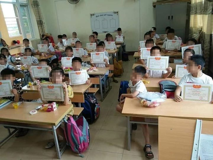 Hình ảnh một cậu học sinh mặt buồn thiu giữa lúc các bạn cùng lớp giơ cao tấm giấy khen làm dấy lên nhiều tranh luận. Ảnh từ Facebook