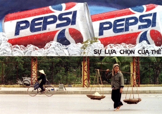 Một người phụ nữ đi qua trước bảng quảng cáo Pepsi ở Hà Nội vào tháng 2/1995, một năm sau khi lệnh cấm vận thương mại được dỡ bỏ. (Ảnh: Reuters)