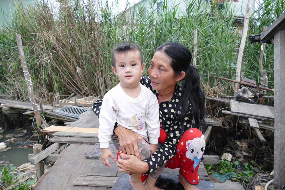 Cô Nguyễn Thị Mai bế đứa cháu nội bị bệnh bướu cổ nhưng vì hoàn cảnh khó khăn nên không đủ tiền chữa trị