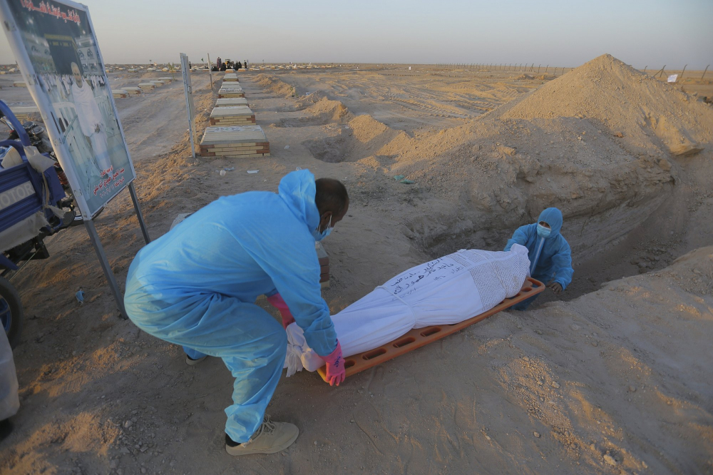 Các thành viên của lữ đoàn Shiite Imam Ali chôn cất thi thể nạn nhân trong một đám tang tại nghĩa trang Wadi al-Salam.