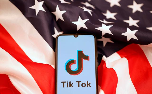 Logo TikTok hiển thị trên điện thoại thông minh trên nền cờ Mỹ - Ảnh minh họa: Reuters