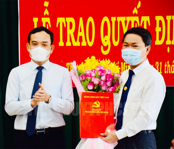 Phó Bí thư Thường trực Thành ủy TP.HCM Trần Lưu Quang trao quyết định và tặng hoa chúc mừng ông Trần Hoàng Quân. Ảnh: Web Thành ủy TP.HCM.