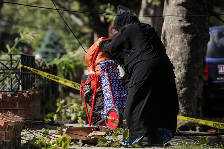 Một người phụ nữ đang cố vượt qua một khu vực bị cây đổ ngã, dây điện đứt