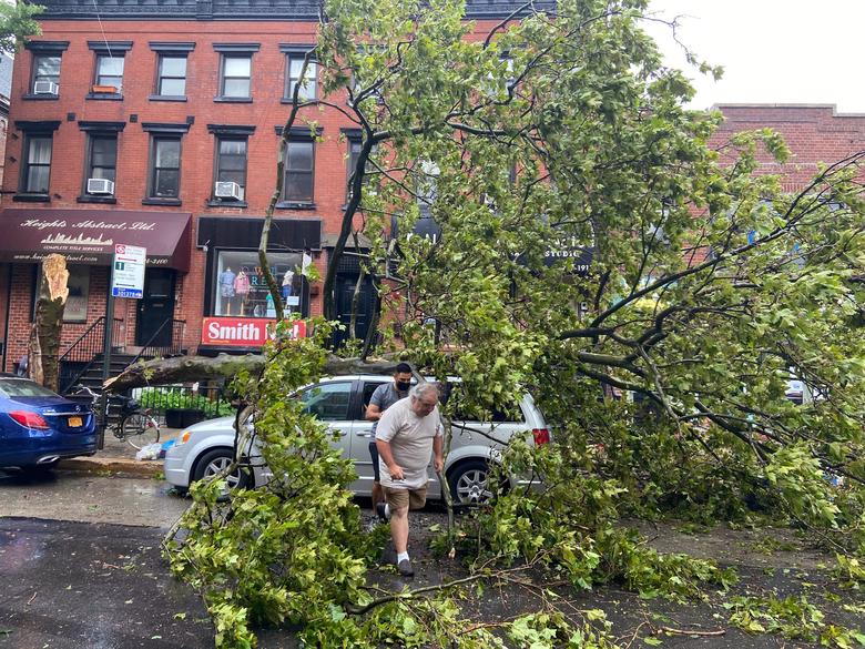 Những cây to lớn đổ ngã trong bão khiến nhiều phương tiện bị đè trúng, giao thông bị ảnh hưởng. Trong ảnh, hai người đàn ông ở Brooklyn, New York 